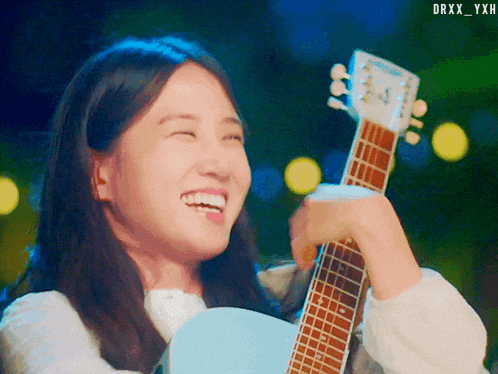 a woman is smiling while holding a guitar with the watermark drxx_yxh on the bottom