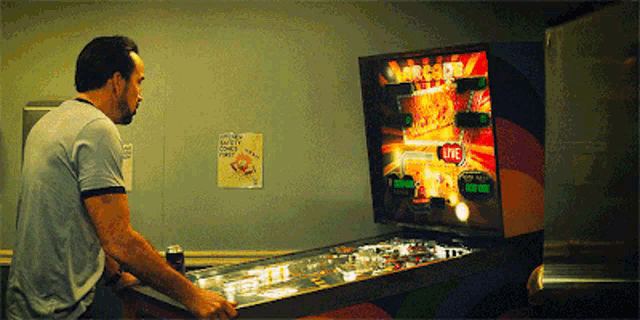 a man is playing a pinball machine that says archer