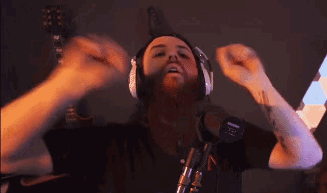a man with a tattoo on his arm is wearing headphones and singing into a microphone .