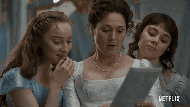 three women are looking at a piece of paper with a netflix logo in the corner