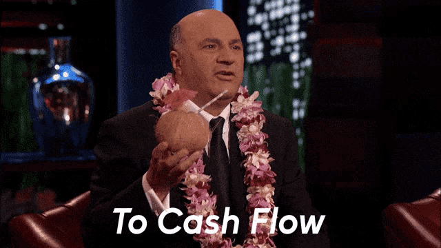 a man with a lei around his neck is holding a coconut with a straw and says to cash flow