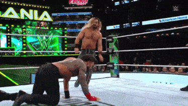 two wrestlers in a ring with a sign that says first trust