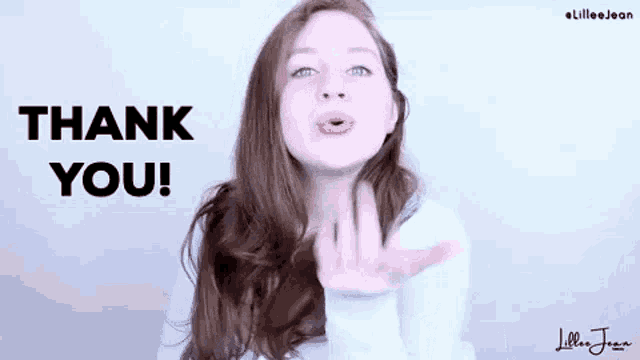a woman is blowing a kiss in front of a sign that says thank you .