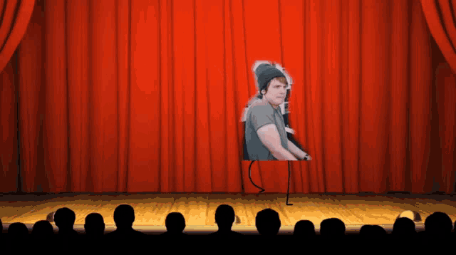a stage with a red curtain and a picture of a man