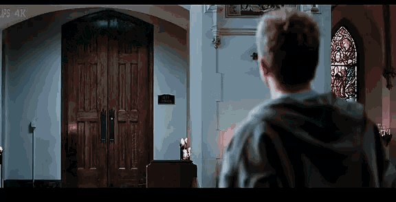 a man stands in front of a church with a sign on the door that says ' sanctuary ' on it