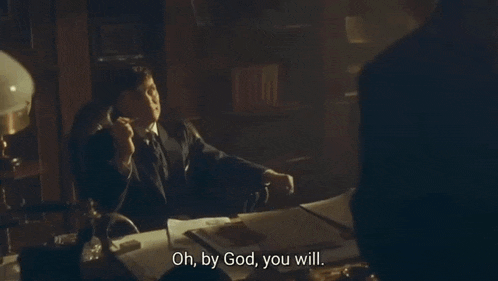 a man in a suit and tie is standing in front of a desk and says oh by god you will