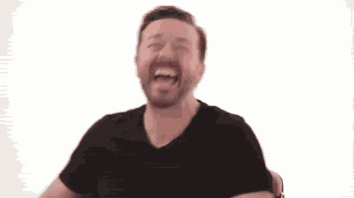 a man with a beard is sitting in a chair laughing .