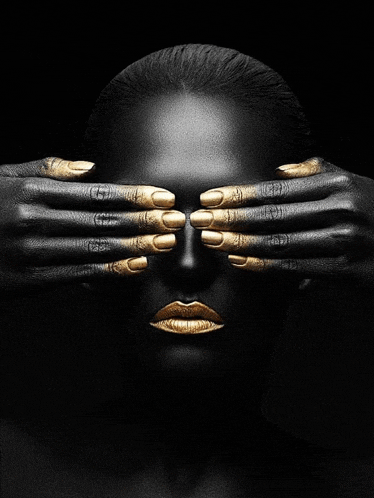a woman with black and gold paint on her face covers her eyes with her hands