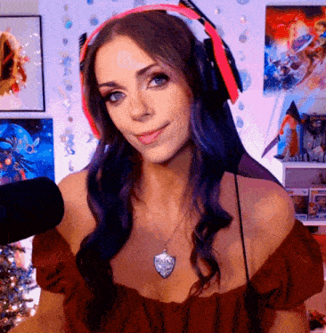 a woman with purple hair wearing headphones and a necklace stands in front of a microphone