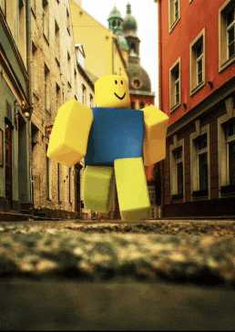 a toy roblox character walking down a street with buildings in the background