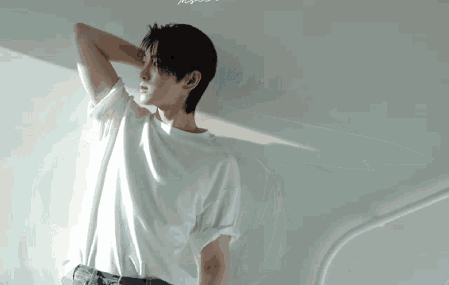 a young man in a white t-shirt is holding his neck