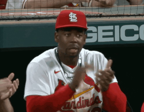 a man wearing a red cardinals jersey is clapping