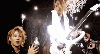 a man is playing a guitar in front of a chandelier in a dark room .