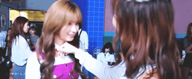 two women are standing next to each other and one of them is touching the other 's face