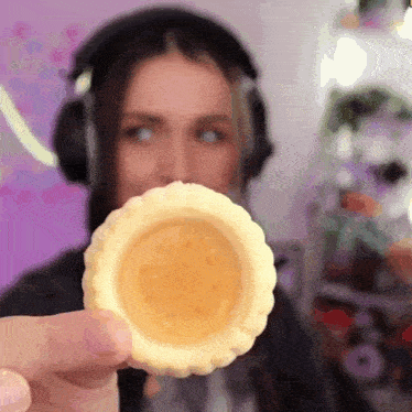 a woman wearing headphones is holding a cookie in front of her mouth