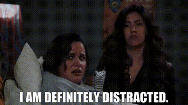 two women are sitting next to each other on a bed and one of them is saying `` i am definitely distracted '' .