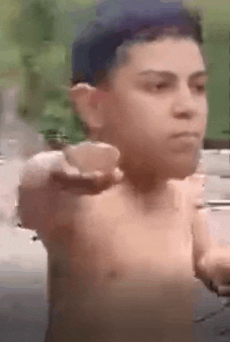 a man without a shirt is pointing at the camera with his hand .