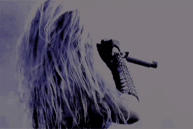 a woman singing into a microphone with spikes on her gloves