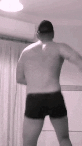 a shirtless man in black shorts and a hat is dancing