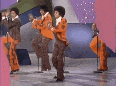 a group of men are dancing on a stage with microphones .