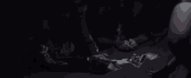 a group of people are sitting around a table in the dark playing cards .
