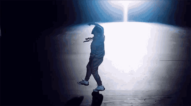 a man is dancing in a dark room with a light shining on him