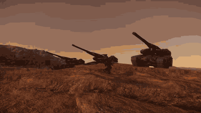 a couple of tanks sitting on top of a hill with mountains in the background