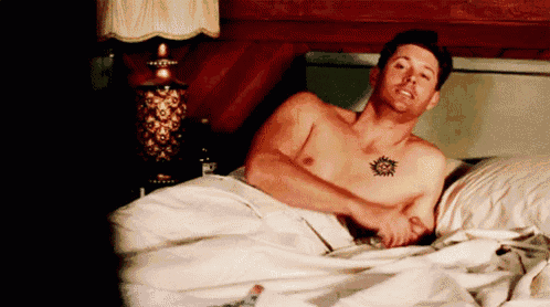 a shirtless man with a tattoo on his chest is laying in bed