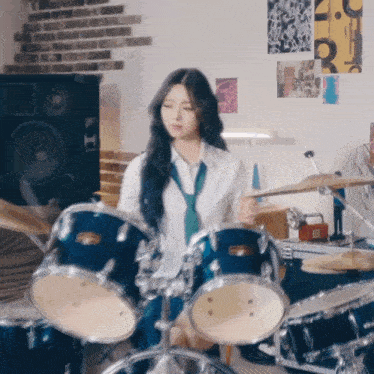 a girl is playing drums in a room with posters on the wall