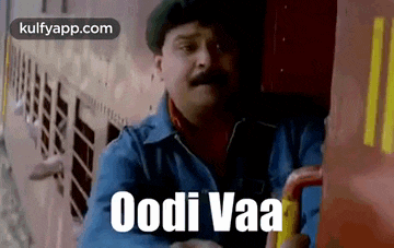 a man with a mustache is sitting on a train with the words oodi vaa written on it .