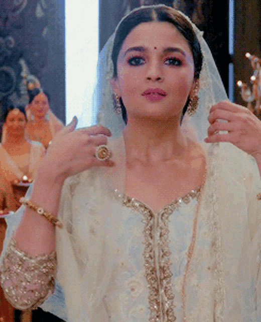 a woman in a white dress has a gold ring on her left hand