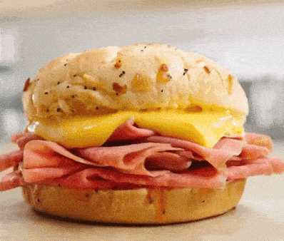a close up of a sandwich with ham and cheese on a bun