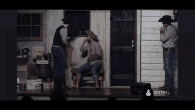 a man in a cowboy hat is standing next to a woman sitting on a bench in front of a building that says central