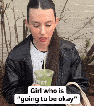 a woman in a black jacket drinking a green smoothie with the words girl who is going to be okay below her