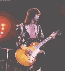 a man is playing a guitar on a stage in a dark room