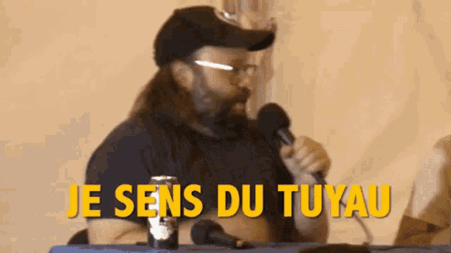 a man with long hair and a beard is holding a microphone and says je sens du tuyau