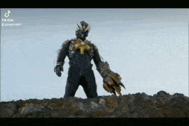 a monster is standing on top of a rocky hill holding a large claw .