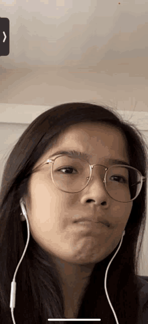 a woman wearing glasses and ear buds making a funny face