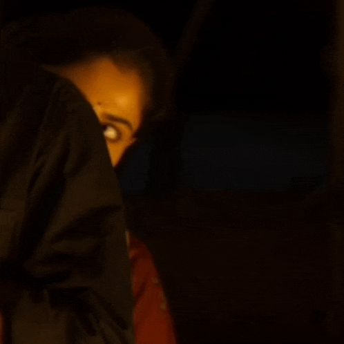 a woman in a red shirt and white scarf is looking up at something