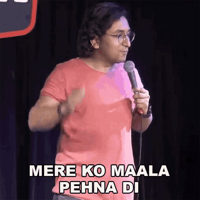 a man in a red shirt is holding a microphone and saying mere ko maala pehna di
