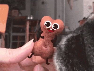 a person is holding a cartoon peanut with big eyes and arms