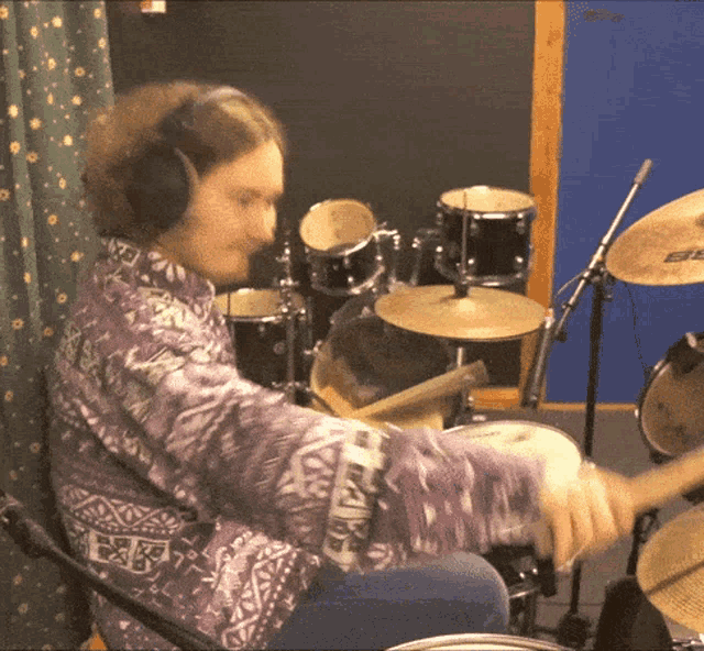 a man in a purple shirt is playing a drum set