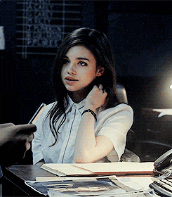 a woman in a white shirt sits at a desk with papers