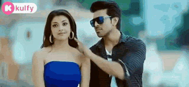 a man is putting his hand on a woman 's shoulder while wearing sunglasses .
