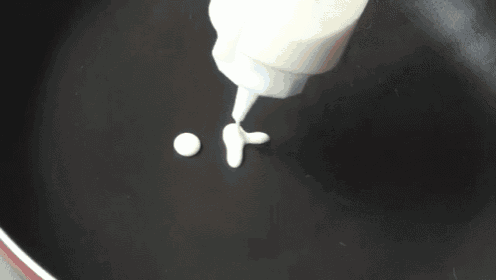 a person is pouring sauce into a frying pan