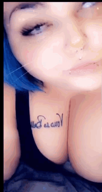 a woman with blue hair has a tattoo on her chest that says ' i love you '