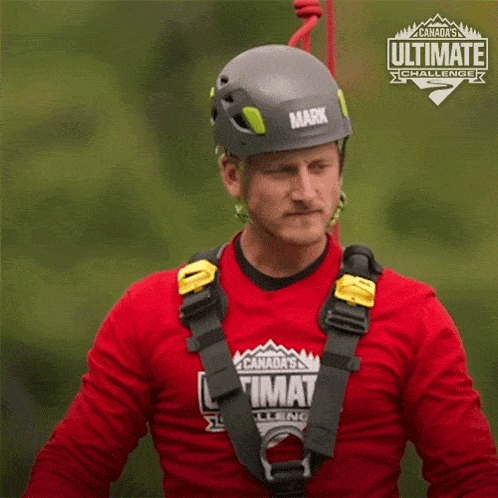 a man wearing a helmet and a red shirt that says canada 's ultimate challenge on it