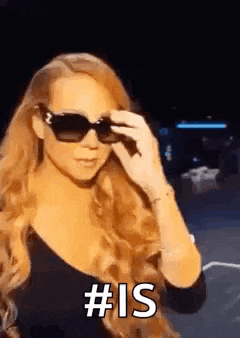 a woman wearing sunglasses and a black top is holding her sunglasses over her eyes .