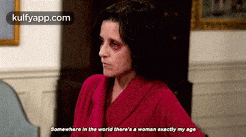 a woman with a black eye and a red robe says somewhere in the world there is a woman exactly my age