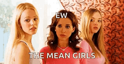 three women are standing next to each other in front of a wall with the words `` the mean girls '' .
